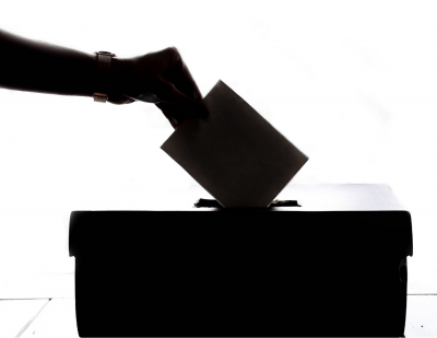 Black and White image of hand dropping ballot into box