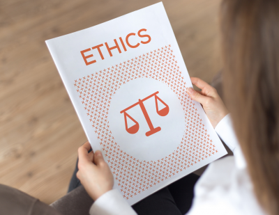 A  person holding a bound document with the title "Ethics" and an image of a weighing scale.